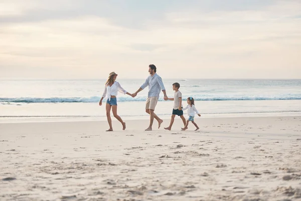 The love in our family flows strong and deep. Full length shot of a happy couple holding hands with their two children and walking along the beach