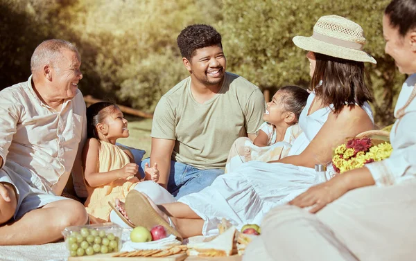 Black family, picnic with food in a nature park in summer happy about quality time together. Happiness of parents, children and elderly people with a smile, love and care outdoor in the sun with kids.