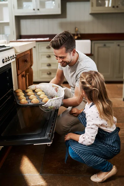 我们如何检查它们是否熟透了 一个小女孩和她的父亲在家里烘焙 — 图库照片