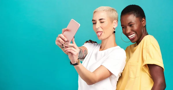 stock image Selfies are better when we take them together. Studio shot of two young women taking selfies together against a turquoise background