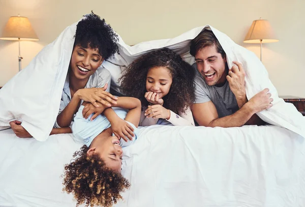 家族と一緒に楽しい一日に目覚めます 幸せな家族が家の毛布の下でリラックスして — ストック写真