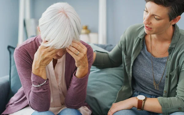 stock image Mum, tell me how to fix this. an attractive young woman sitting and comforting her senior mother while she suffers from a headache