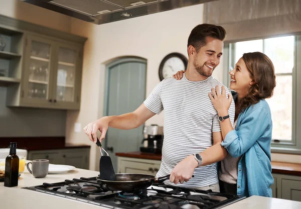 What did I do to deserve such a perfect partner. a young woman embracing her partner while he cooks breakfast
