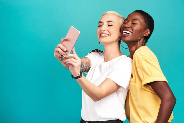 The best thing life gave me was my bestie. Studio shot of two young women taking selfies together against a turquoise background