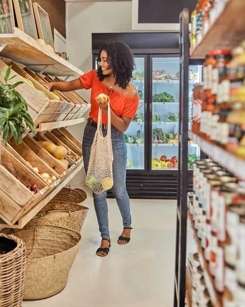 Supermarket, black woman and grocery shopping for fruit, vegetables and healthy produce at a local store. Happy, relax and customer choosing organic, vegetarian and vegan items for salad or diet.