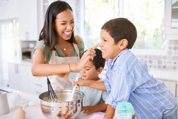 Family baking and mother teaching children to bake cake in the kitchen of their home. Happy latino kids and woman play, cooking and laugh together while learning about food and being playful in home.