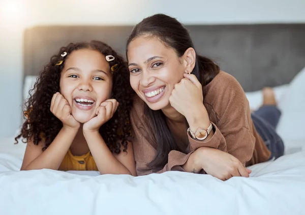 Happy, relax and portrait of mother and girl with smile on the bed in bedroom together in family home. Happiness, love and woman from Mexico laying with her child to rest, relax and bond at the house.