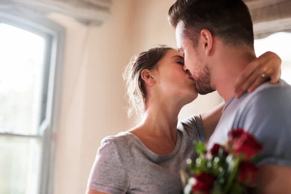 我们每时每刻都在接吻一个年轻人带着一束玫瑰在他的卧室里给他的女朋友一个惊喜 — 图库照片