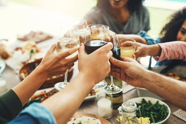 Drinks up everybody. a group of unrecognizable people joining their glasses together for a toast while enjoying a meal together outdoors