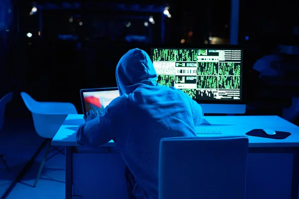Getting ready to unleash another cyber attack. Rearview shot of a male hacker cracking a computer code in the dark
