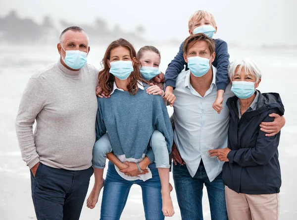 Covid, family and ocean portrait with children in Germany with corona virus protection mask. Love, care and big family bonding at beach with coronavirus face mask for safety of grandparents