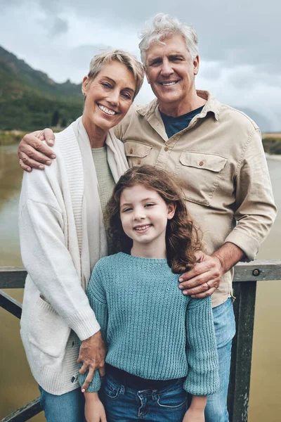 Family, grandparents and child being happy, bonding and vacation with smile, holiday or together outdoor. Portrait, grandfather and grandmother with girl to relax, embrace and on road trip for travel.