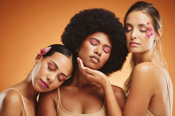 Beauty, diversity and skincare with a model woman friends in studio on an orange background for wellness. Health, skin and cosmetics with a female group posing to promote a product or treatment.