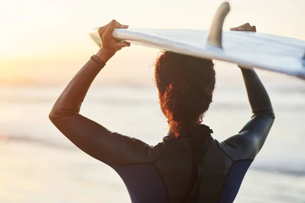 広大な海に自由があります ビーチで彼女の頭の上にサーフボードを運ぶ女性サーファーのレビューショット — ストック写真