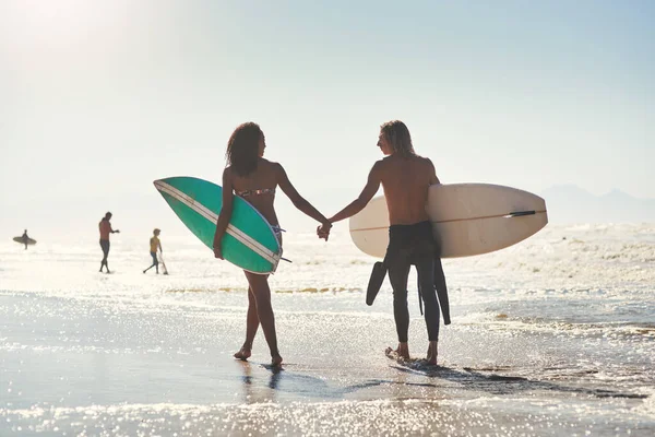 サーフィンは両方とも楽しむことができるものです 若いカップルがサーフボードを持ってビーチで一日を過ごし — ストック写真