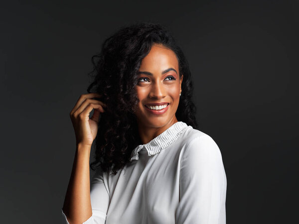 Never seen a smiling face that wasnt beautiful. Studio shot of an attractive young woman wearing a white blouse and posing and smiling against a dark background