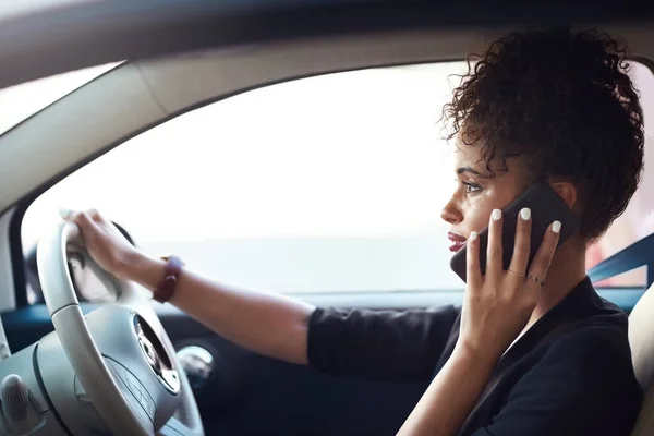 stock image Getting things done on the move. an attractive young businesswoman taking a phonecall while driving her car