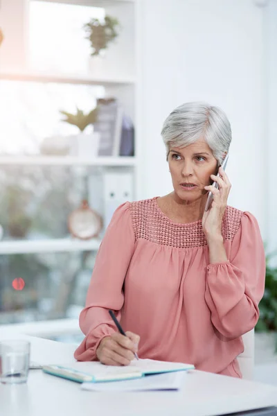 Stock image Shes using all her experience to deal with the matter. mature businesswoman taking a phone call at her office desk at work