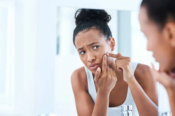 stock image I cant go out with this. a beautiful young woman squeezing a pimple in the mirror