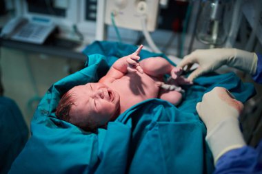 Dünyaya hoş geldin tatlı melek. Hastanede tıbbi personelle çevrili yeni doğmuş bir kız bebek.