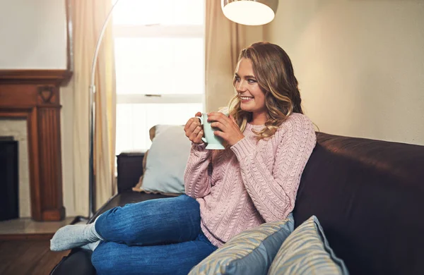 Sit back and sip on some coffee. a relaxed young woman having coffee on the sofa at home