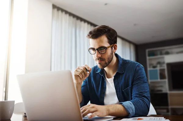 专注和决心是实现你目标的关键 一位年轻英俊的商人在家里工作时坐下来用他的笔记本电脑 — 图库照片
