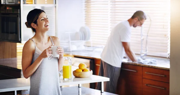 Stock image I love when its your turn to do the dishes, honey. a woman drinking coffee while her husband washes dishes in the background at home