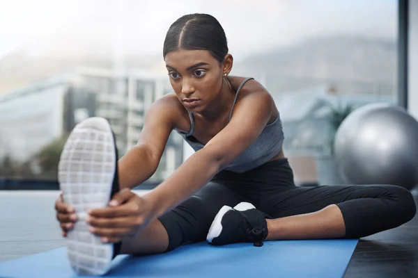 stock image Staying focused is the biggest aspect of staying in shape. an attractive young woman sitting down and doing stretching exercises on her gym mat at home