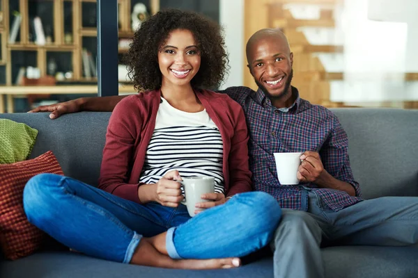 Coffee time is quality time. Portrait of a happy young couple enjoying a relaxing coffee break together on the sofa at home