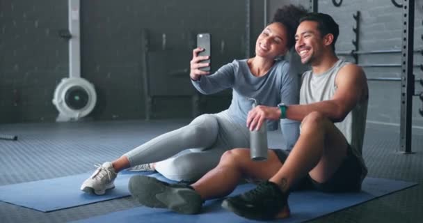 セルフィー アクティブなカップルは トレーニングワークアウトから休憩してスマートフォンの写真を撮る フィットネス 健康と運動センターで写真を撮る黒のカップルとモバイルウェルネス — ストック動画