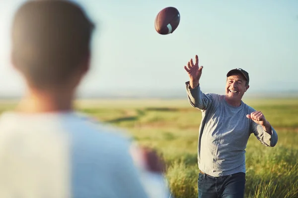 Stock image We have so much fun even when just tossing a ball. father throwing a football to his son on a field