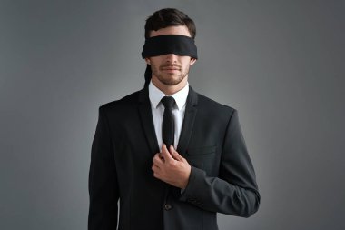Trust the unseen. Studio shot of a young businessman wearing a blindfold against a gray background