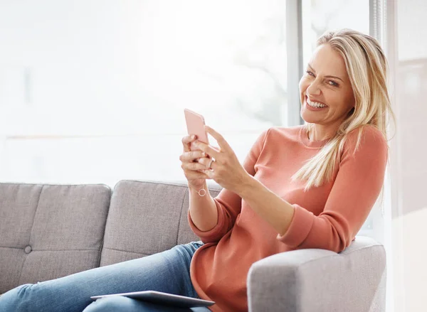 stock image Taking a break but still available on my cell. Portrait of an attractive mature woman using a mobile phone while relaxing on the sofa at home