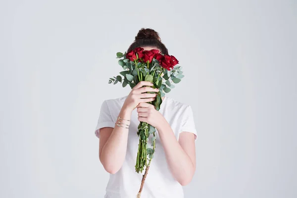 stock image Flowers are loves truest language. Studio shot of an unrecognizable woman covering her face with flowers against a grey background