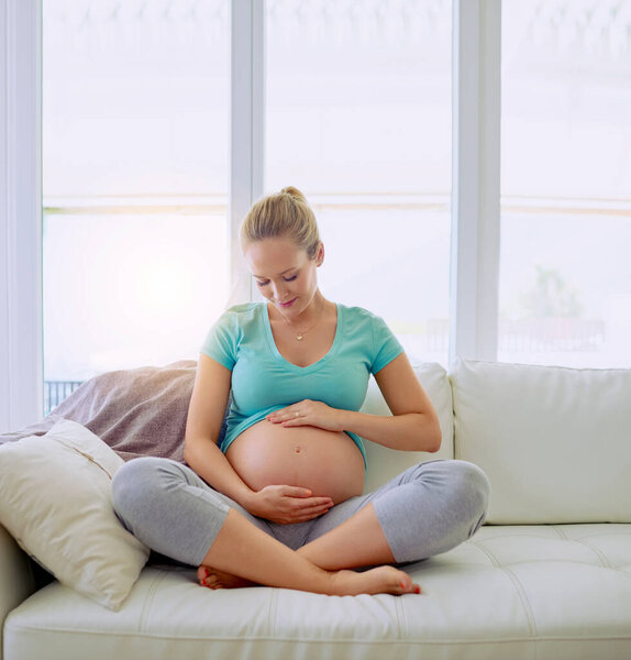 Bonding with her bundle of joy. a pregnant woman holding her belly at home