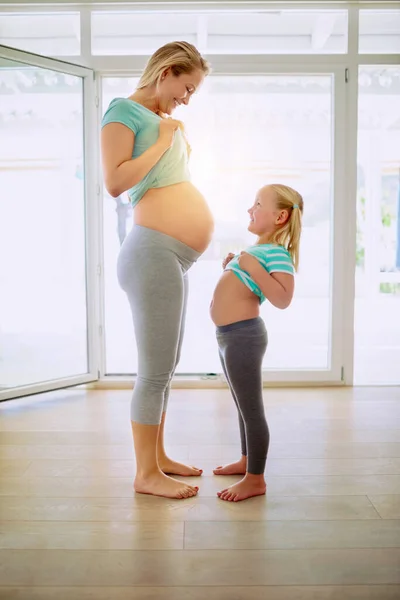 你也想看看我的肚子吗 一个孕妇和她的小女儿在家里互相展示她们的胃 — 图库照片