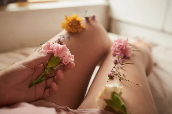 Szép Lábak Még Szebbek Egy Azonosítatlan Fiatal Fekszik Ágyban Virágokkal — Stock Fotó