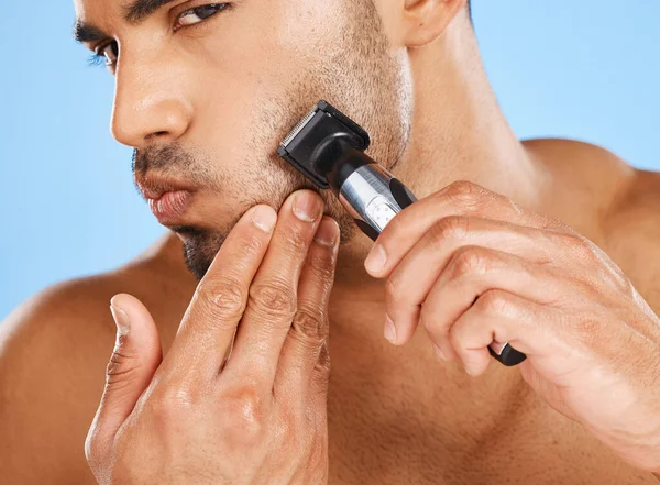 Beauty, skincare and man shaving beard in his grooming routine with an electric machine in a studio in Mexico. Wellness, Latino and healthy male model shaves his facial hair with a cool modern razor.