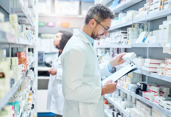 stock image Treatment begins with them. a mature man doing inventory in a pharmacy with his colleague in the background