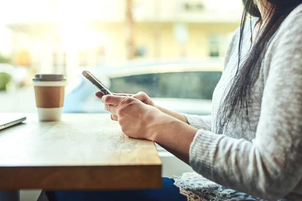 stock image Connectivity with a side of coffee. Closeup shot of an unrecognizable woman using a cellphone in a cafe