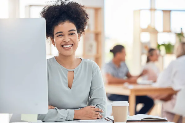 Happy, satisfied and confident with a black woman in business sitting at her desk in the office. Company, success and vision with a happy female employee working on a computer with a carefree smile.