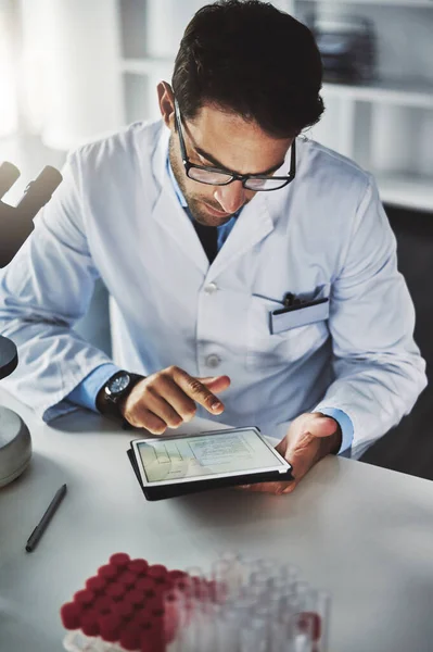 He records every detail on his device. a scientist using a digital tablet while working in a lab