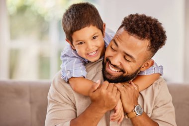 Baba, çocuk oyunu ve aile kucaklaşması bir ebeveyn ve çocuğun oturma odasındaki kanepede oturması. Baba ve çocuk mutlu bir gülümseme ile bir kanepede sabahleyin bir evde birlikte güzel vakit geçiriyorlar..