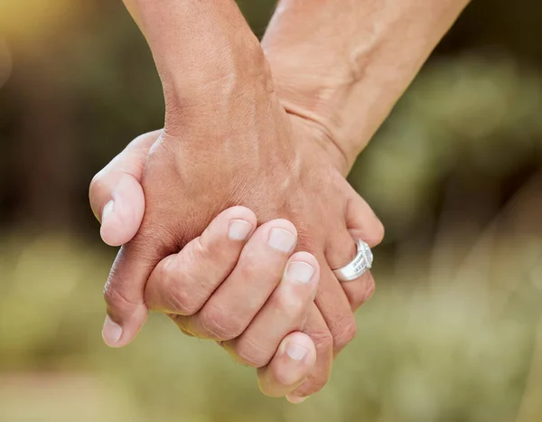 Couple, hands closeup and marriage love together bonding outdoors in bokeh background. Senior man, married woman and trust loving loyalty support romance care kindness or respect in nature park.