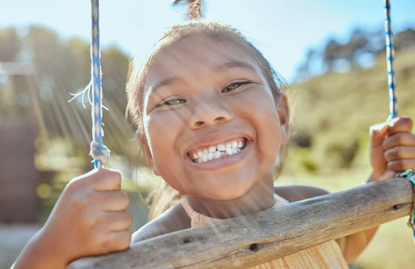 歯と屋外公園でスイングに小さな女の子 幸福とインドネシアで外で遊んでいます 幸せな顔 夏休みに自宅で庭で揺れる若い子供の肖像画 — ストック写真