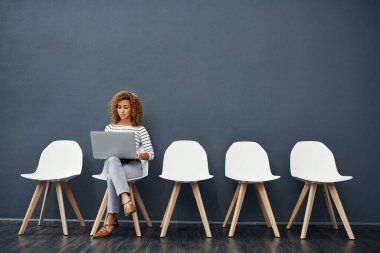 Beklerken bağlantıda kalmak. Çekici bir genç kadının iş görüşmesi sırasında dizüstü bilgisayar kullanırken tam boy fotoğrafı.