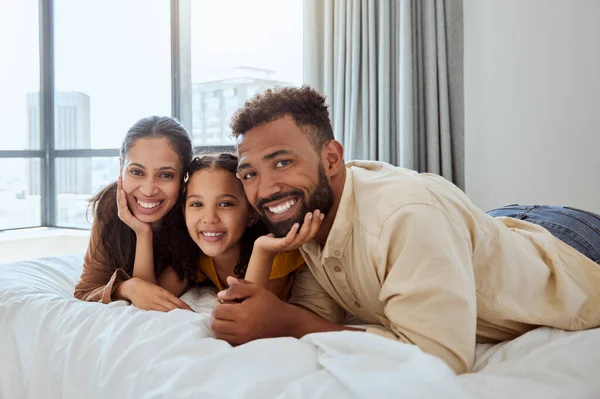 Family, hug and smile, parents and child lying on bed in portrait, love and care together, home and bonding. Mother, father and girl kid happy, bedroom and spending quality time in family home
