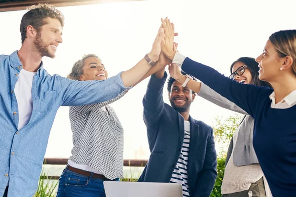 Stock image No matter what, well always come out on top. a group of businesspeople high fiving during a meeting outdoors