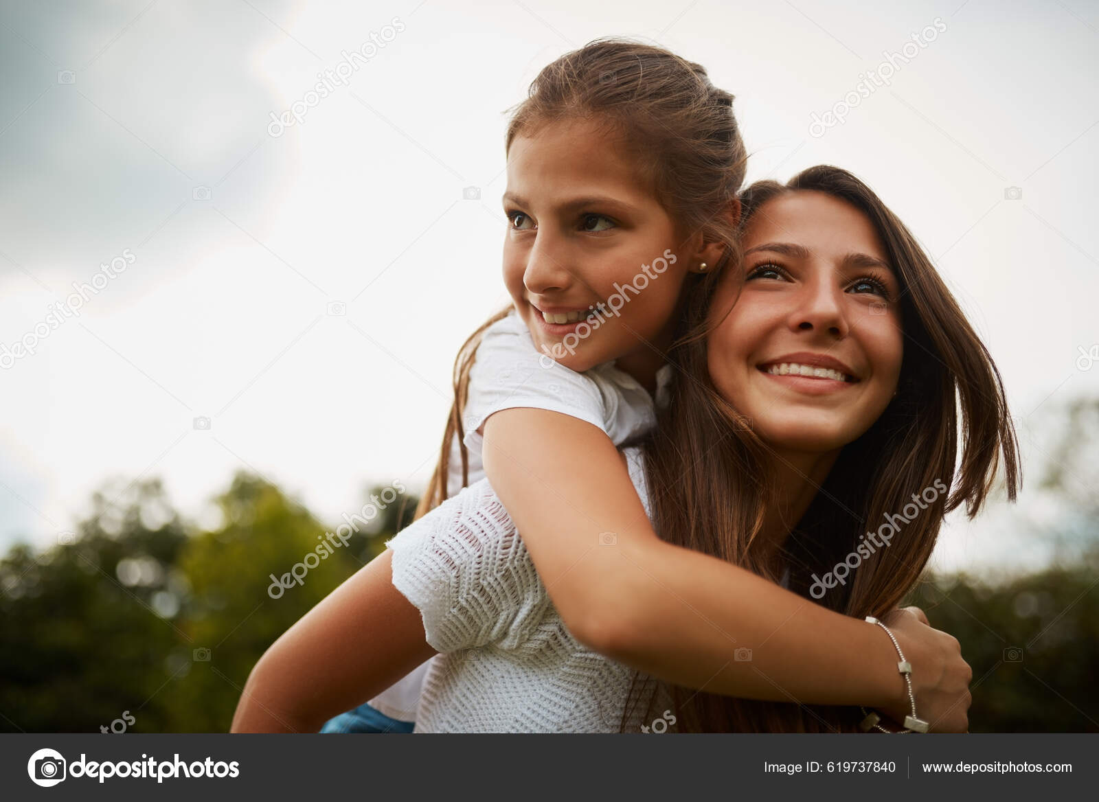 Young girl carrying sister giving piggyback ride Stock Photo