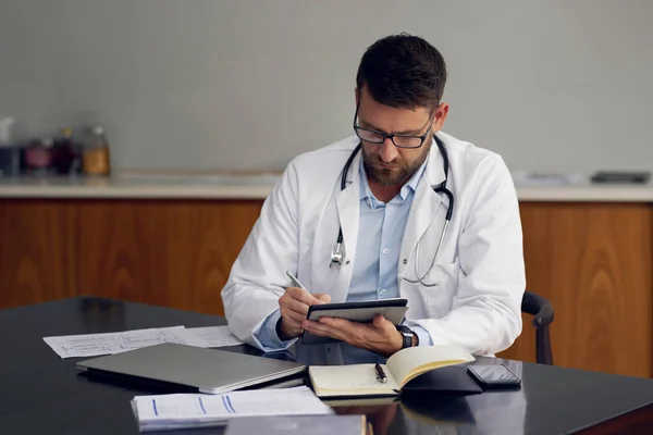 Wireless technology makes record-keeping a breeze. a handsome male doctor working on his tablet while sitting in his office